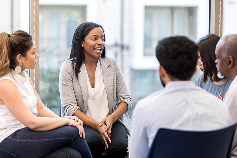 Young woman leading group therapy session.