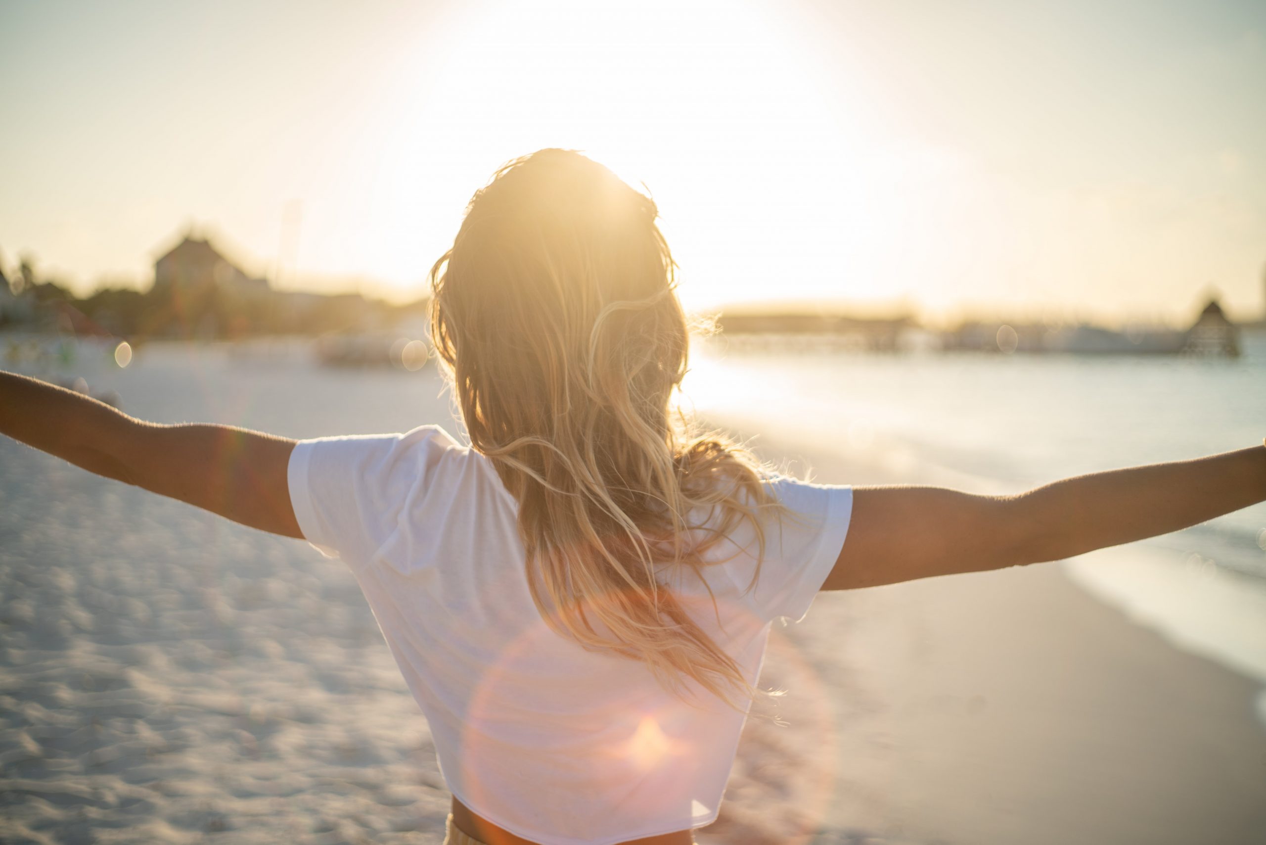 woman with arms open standing in front of ocean