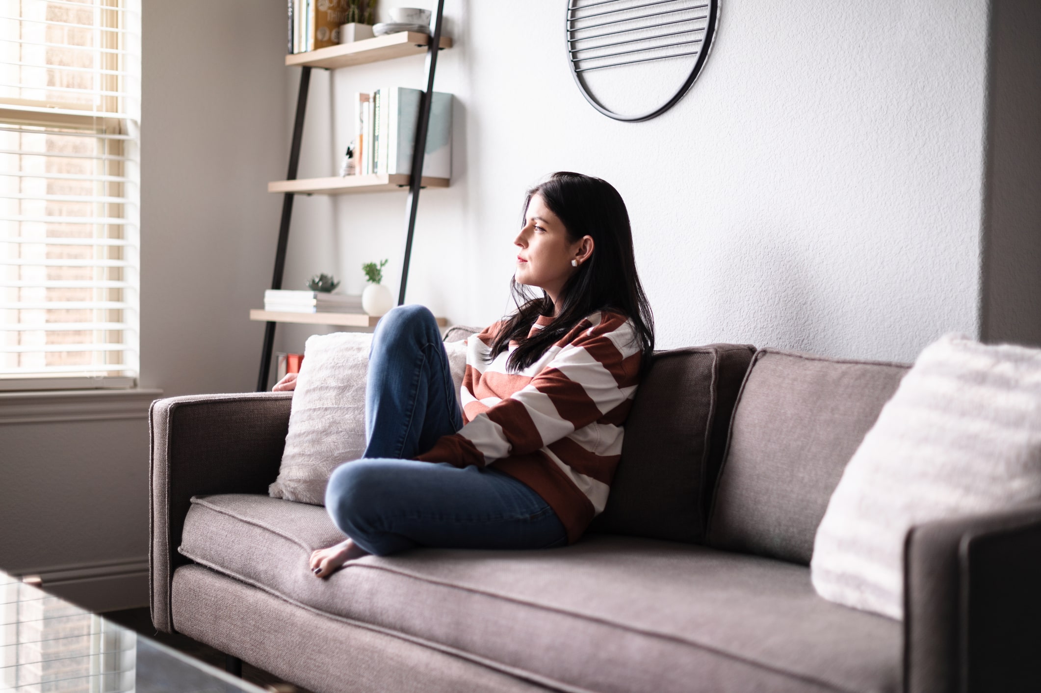 Woman sitting on couch looking out window