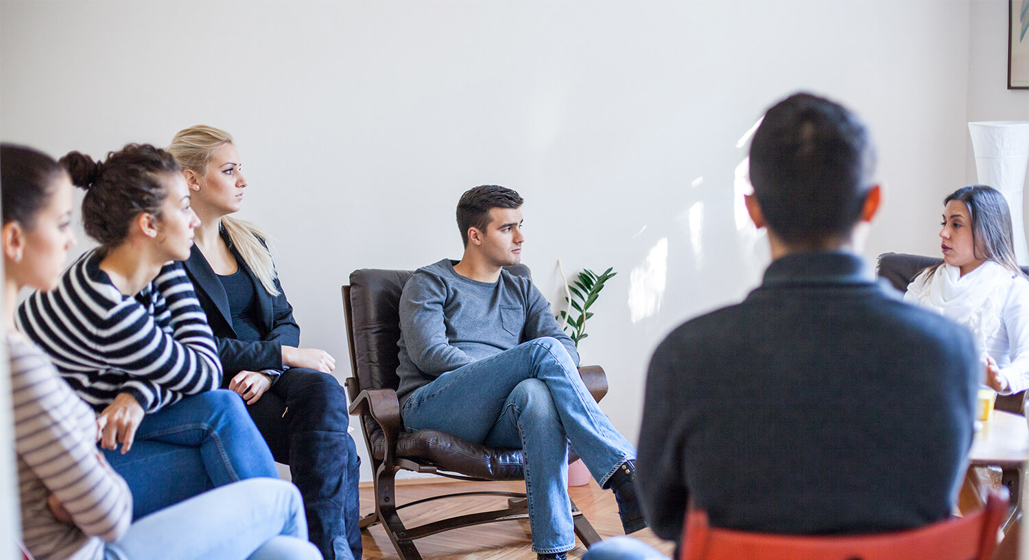 Members of a group therapy session listening to another member